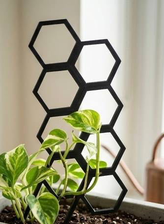 Black stackable 3D printed honeycomb plant trellis supporting a small variegated houseplant